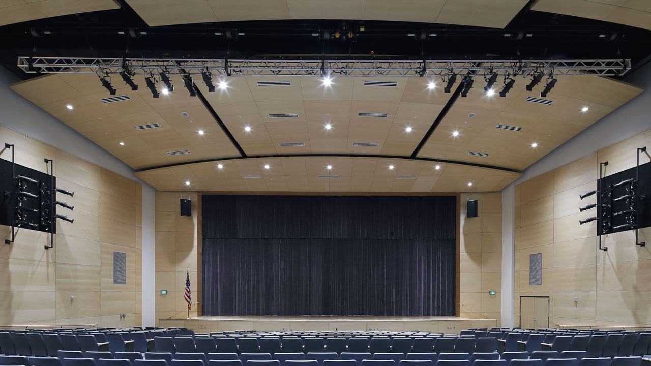 An image of a large auditorium. Walls and ceiling are lined with acoustical panels.
